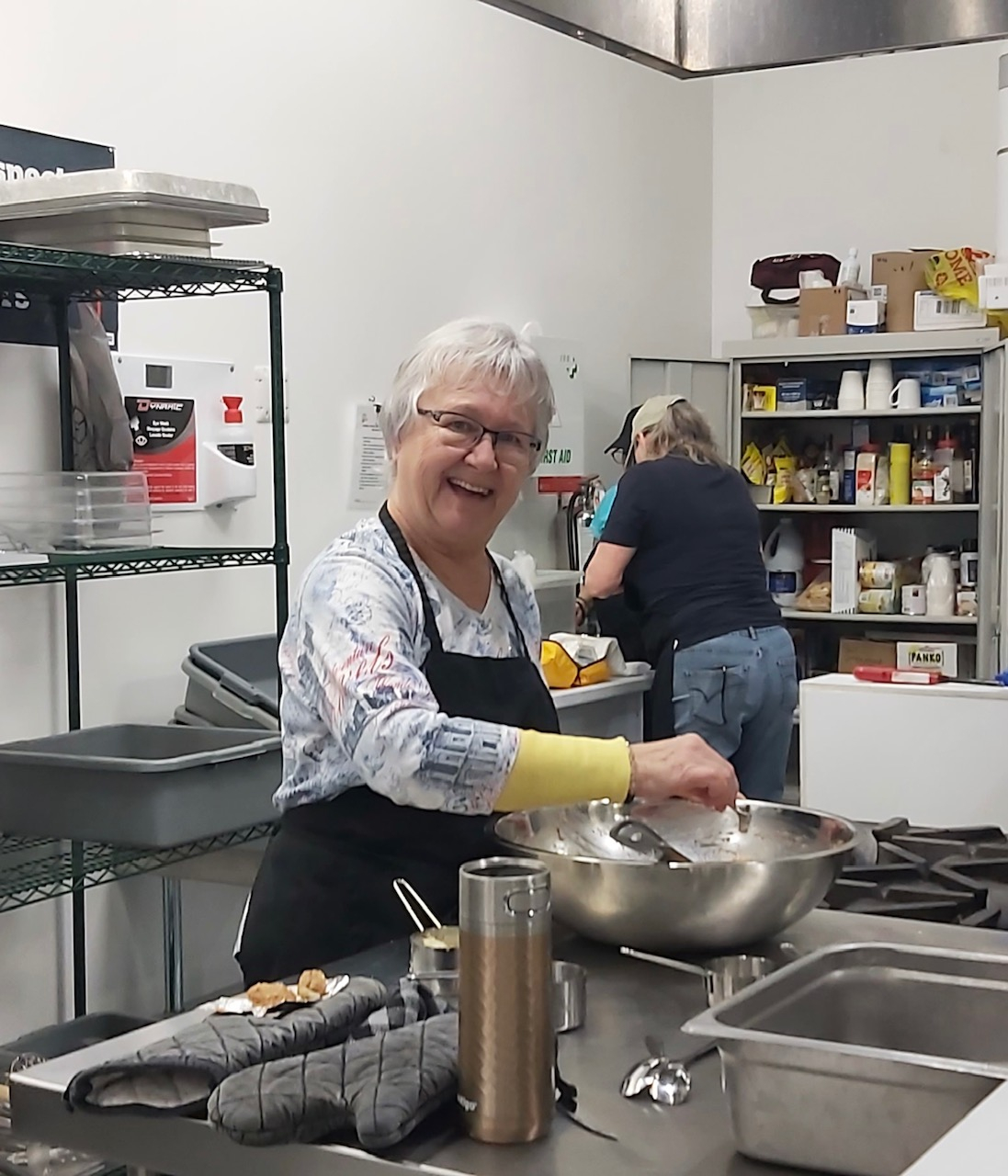 A group of seniors happily cooking together in a kitchen.